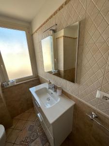 ein Badezimmer mit einem Waschbecken, einem Spiegel und einem WC in der Unterkunft Appartamento Cataleya Home in Brindisi