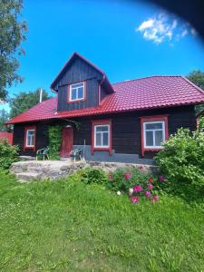 a house with a red roof and a yard with flowers at Zirgu sēta "Klajumi" - Horse ranch "Klajumi" in Kaplava