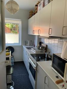a small kitchen with white cabinets and a window at Nice room near airport in Copenhagen