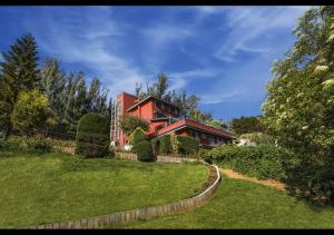 uma casa vermelha numa colina com um quintal em Willow Hill by Nature Resorts em Ooty