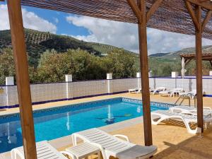 a swimming pool with white lounge chairs and a swimming pool at Casa Pino Solo in Iznájar