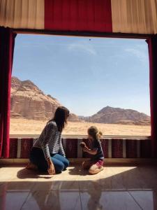 uma mulher e uma criança sentados em frente a uma janela em Enad desert camp em Wadi Rum