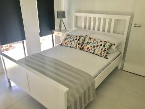 a white bed with a pillow on it in a bedroom at Kuyu Kuyu House in Port Douglas