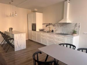 uma cozinha com armários brancos e uma mesa e cadeiras em Apartamentai Jums em Telsiai