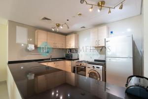 a kitchen with a white refrigerator and a dishwasher at Pristine 1 Bedroom In Tala Tower in Abu Dhabi