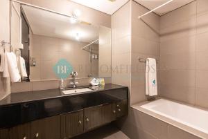 阿布達比的住宿－Pristine 1 Bedroom In Tala Tower，一间带水槽、浴缸和镜子的浴室