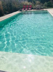 una piscina de agua azul con sillas rojas. en Chez Nelly : Escapade campagne Toulousaine en Bessières