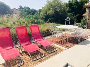 vier rode stoelen en een tafel in een tuin bij Chez Nelly : Escapade campagne Toulousaine in Bessières