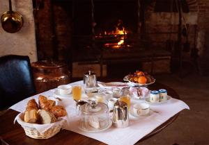 a table with a breakfast of croissants and coffee and a fireplace at Le château de Bonnemare - Bed and breakfast in Radepont