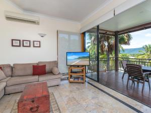 a living room with a couch and a flat screen tv at The Point Villa 10 in Port Douglas