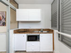 eine Küche mit einer Spüle und einer Mikrowelle in der Unterkunft Portside Studio in Port Douglas