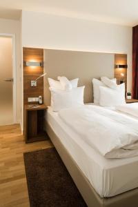 ein großes Bett mit weißer Bettwäsche und Kissen in der Unterkunft Living Apartments Ludwigshafen in Ludwigshafen am Rhein
