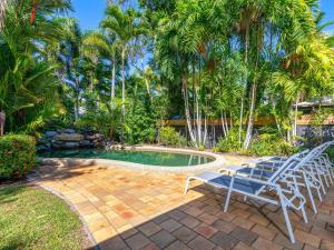 een zwembad met stoelen en palmbomen in een tuin bij Blue Sage in Port Douglas