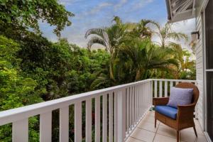 uma varanda com uma cadeira e palmeiras em Beach Villa 3 em Port Douglas