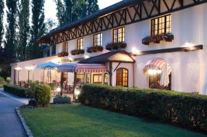 un edificio blanco con mesas y sombrillas en un patio en LOGIS Le Pot D'Etain, en Holnon