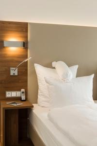 ein Bett mit weißen Kissen und einem Tisch mit einer Lampe in der Unterkunft Living Apartments Ludwigshafen in Ludwigshafen am Rhein