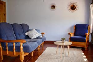 ein Wohnzimmer mit einem blauen Sofa und 2 Stühlen in der Unterkunft Casa Rural la Laguna 