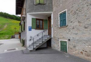 un edificio con escaleras, ventanas y una puerta verde en Appartamento Scialket en Livigno
