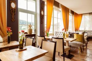 un restaurante con mesas, sillas y ventanas en STEIGER Hotel Elbschlösschen Rathen, en Kurort Rathen