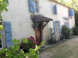 a white house with blue windows and a door at une fermette climatisée en pleine nature in Moirax