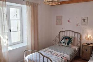 ein kleines Bett in einem Zimmer mit Fenster in der Unterkunft Le Clos de Fanny - Belle longère charentaise in Burie