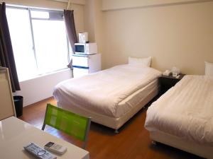 a hotel room with two beds and a table and a chair at Shimakaigetsu in Sumoto