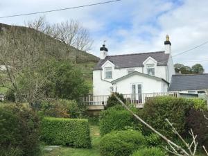 a white house with a fence and bushes at Gorffwysfa Cottage, Garnfadryn, nr Abersoch in Dinas