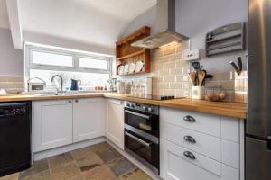 a kitchen with white cabinets and a black dishwasher at Gorffwysfa Cottage, Garnfadryn, nr Abersoch in Dinas