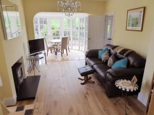 a living room with a leather couch and a table at Pump Cottage in Weymouth