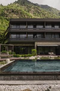 une maison avec une piscine en face d'une montagne dans l'établissement Klein Fein Hotel Anderlahn, à Parcines