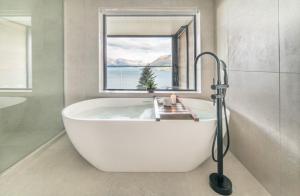 a white bath tub in a bathroom with a window at Kamana Lakehouse in Queenstown