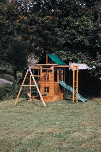 a wooden playground with a slide in the grass at Holiday House Smilja in Ogulin
