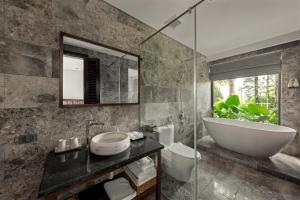 a bathroom with a tub and a sink and a mirror at Coco Island Villa & Hotel Ninh Bình in Ninh Binh