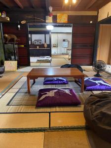 sala de estar con mesa de madera y almohadas púrpuras en 楽園晩御飯(rakuyenbangohan), en Yame
