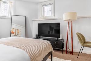 a bedroom with a bed and a tv and a chair at Back Bay Studio steps from Newbury T BOS-557 in Boston