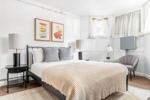 a white bedroom with a bed and a chair at Back Bay Studio steps from Newbury T BOS-557 in Boston