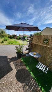 a table and chairs with an umbrella and a fence at Gite moderne et calme in Moncel-sur-Seille