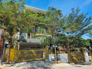 a house with a yellow gate in front of trees at RUBY 2 LUXURY VILLA by NEST GROUP in Nha Trang
