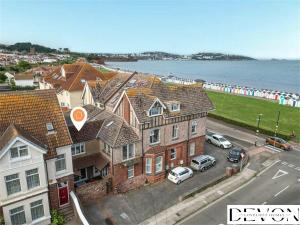 a group of houses with cars parked in front of the beach at Loveliest Homes Paignton - Casa Marina - 3 bed, 2 bathroom house, balcony, parking in Paignton