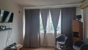 een woonkamer met een raam met gordijnen en een stoel bij Apartman Bella Ilidža in Sarajevo