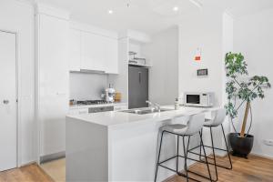 墨爾本的住宿－Southbank ONE - 2Br Apartment，白色的厨房配有水槽和2个酒吧凳