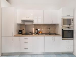 eine weiße Küche mit weißen Schränken und einer Mikrowelle in der Unterkunft The Best Rent - Bright flat near San Pietro in Rom