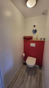 a bathroom with a white toilet and a red wall at Gite moderne et calme in Moncel-sur-Seille +4 photos