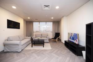 uma sala de estar com dois sofás brancos e uma televisão em Riggae Tower Hotel em Kuwait