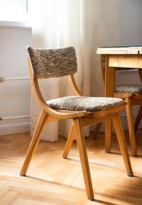 una sedia in legno seduta accanto a un tavolo di Plac Zbawiciela 3-Bedroom Apartment a Varsavia