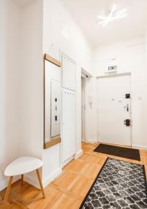 a hallway with white walls and a white chair and a rug at Plac Zbawiciela 3-Bedroom Apartment in Warsaw
