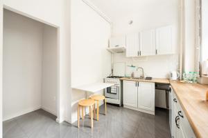 a white kitchen with white cabinets and wooden counters at Plac Zbawiciela 3-Bedroom Apartment in Warsaw