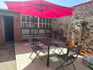 - une table et des chaises avec un parasol rouge sur la terrasse dans l'établissement Central village house in Bussiere Poitevine, à Bussière-Portevine