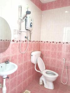 a pink bathroom with a toilet and a sink at Vive Inn in Kuah