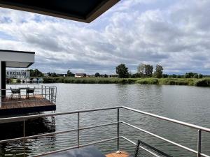 a boat on a river with a deck with a table at Schwimmende Häuser im BALTIC SEA RESORT in Kröslin